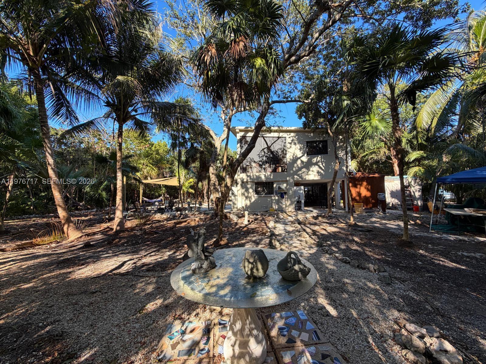 A sunroom features wicker furniture, a stone fireplace with a television, and large windows — 1615 Harbor Dr, Marathon FL 33050, MARATHON, FL