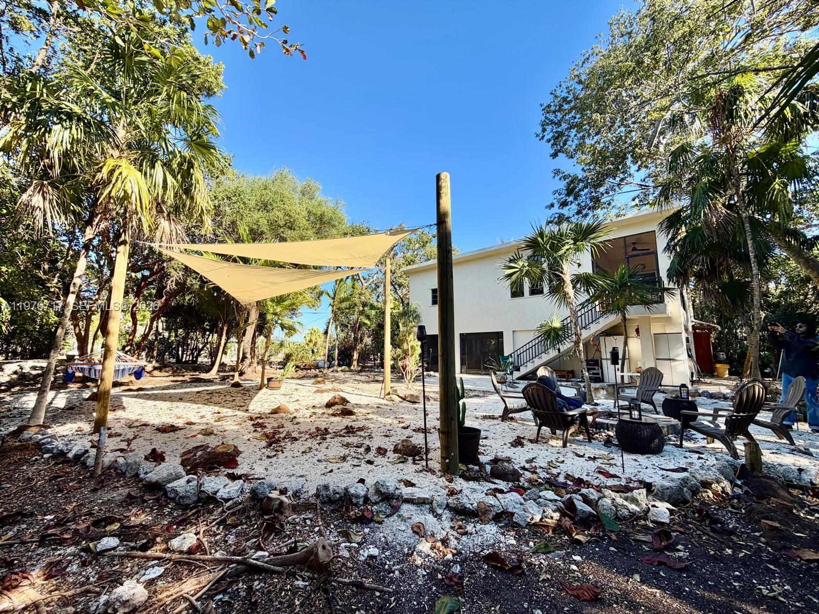 A living room features a live-edge wooden table, wicker furniture, a fireplace, and large windows — 1615 Harbor Dr, Marathon FL 33050, MARATHON, FL
