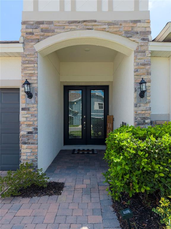 A stone-accented entryway features a double front door, a paved walkway, and exterior lighting — 600 AVILA PLACE, HOWEY IN THE HILLS, FL