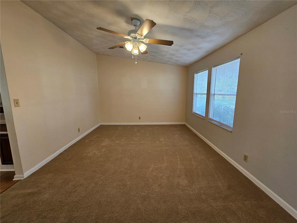 An empty room with beige carpet, tan walls, a ceiling fan, and two windows — 2344 SE 175TH TERRACE, SILVER SPRINGS, FL