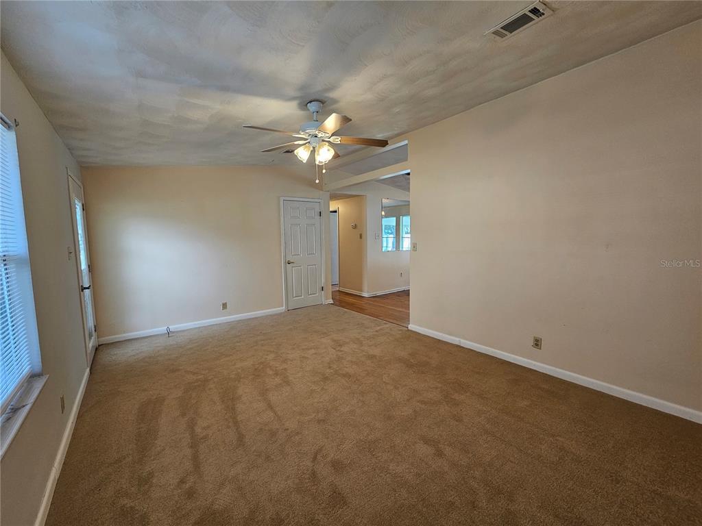 A carpeted living room features a ceiling fan, a white door, and an adjacent hallway — 2344 SE 175TH TERRACE, SILVER SPRINGS, FL
