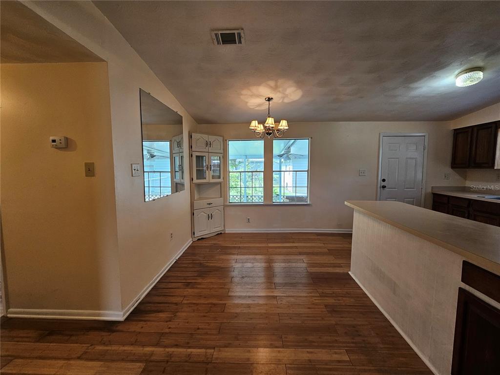 A dining area features wood-look flooring, a corner hutch, a chandelier, and a breakfast bar — 2344 SE 175TH TERRACE, SILVER SPRINGS, FL