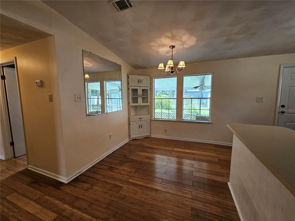 A dining area features wood-look flooring, a corner hutch, a wall mirror, and a chandelier — 2344 SE 175TH TERRACE, SILVER SPRINGS, FL