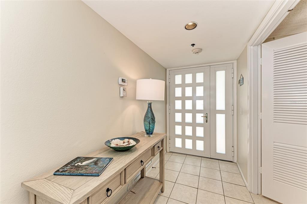 An entryway features a light wood console table, a blue lamp, and a white door — 1135 GULF OF MEXICO DRIVE UNIT 504, LONGBOAT KEY, FL