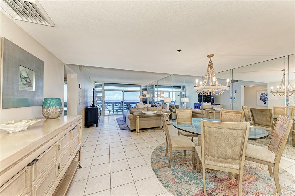 A dining area with a glass table and chandelier opens into a living room with ocean views — 1135 GULF OF MEXICO DRIVE UNIT 504, LONGBOAT KEY, FL
