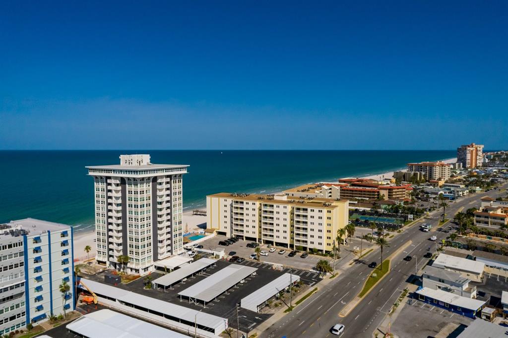An aerial view of beachfront high-rise condominiums and a coastal road under a clear sky — 17408 GULF BOULEVARD UNIT 203, REDINGTON SHORES, FL