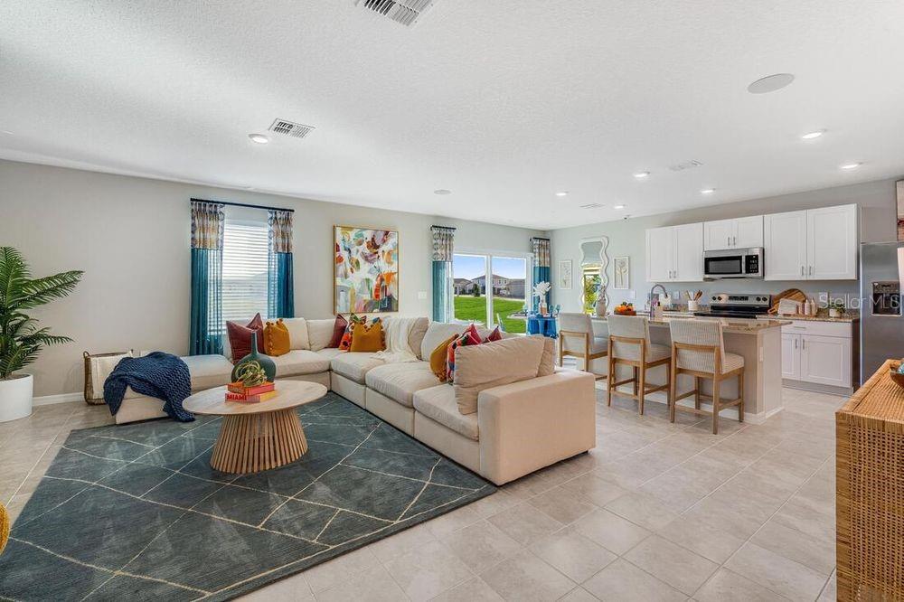 An open-concept living room and kitchen featuring a large sectional sofa and kitchen island — 12422 WHISK COURT, HUDSON, FL