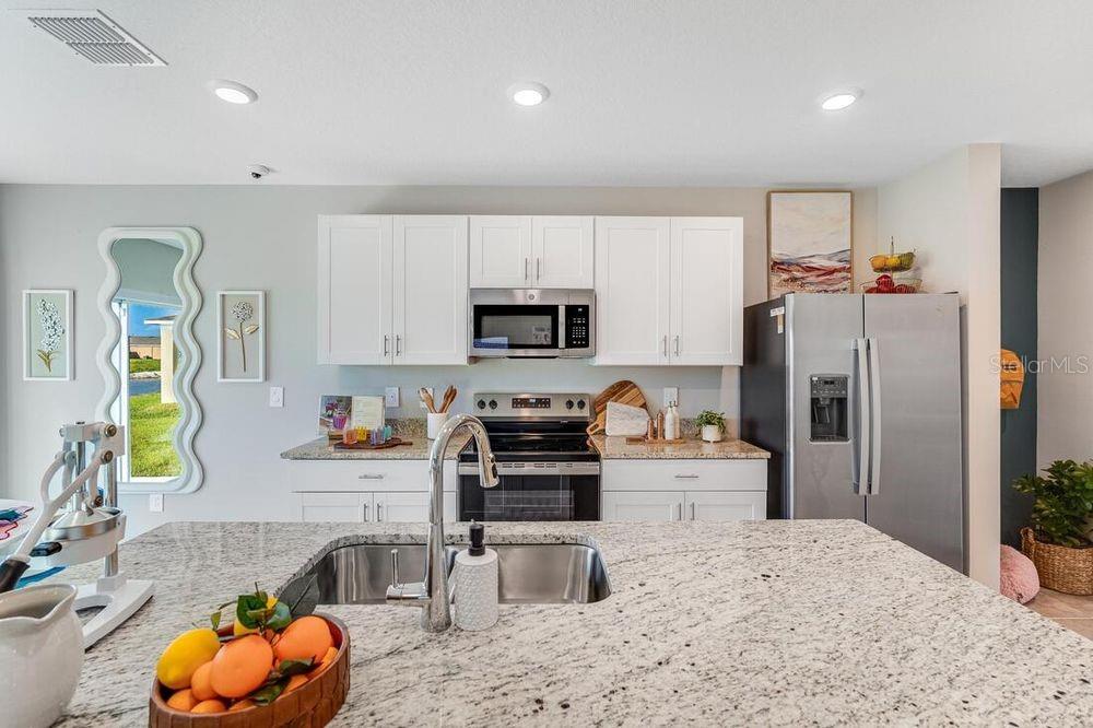 A kitchen features white cabinets, stainless steel appliances, granite countertops, and a large island — 12422 WHISK COURT, HUDSON, FL