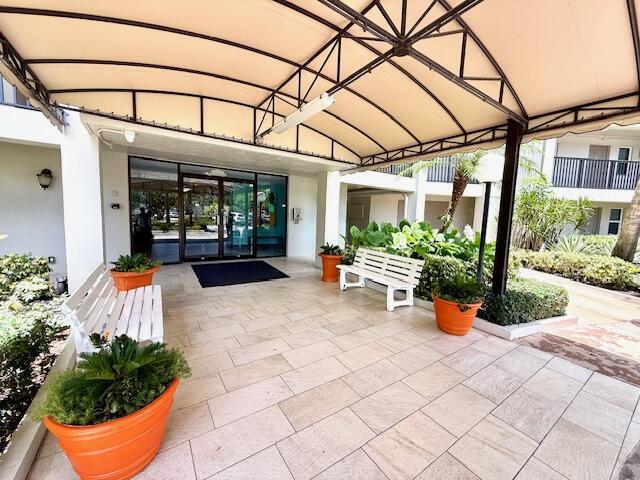 A covered entryway features a tiled patio, two white benches, and large orange planters — 2681 S Course Drive # 712, Pompano Beach FL 33069, POMPANO BEACH, FL