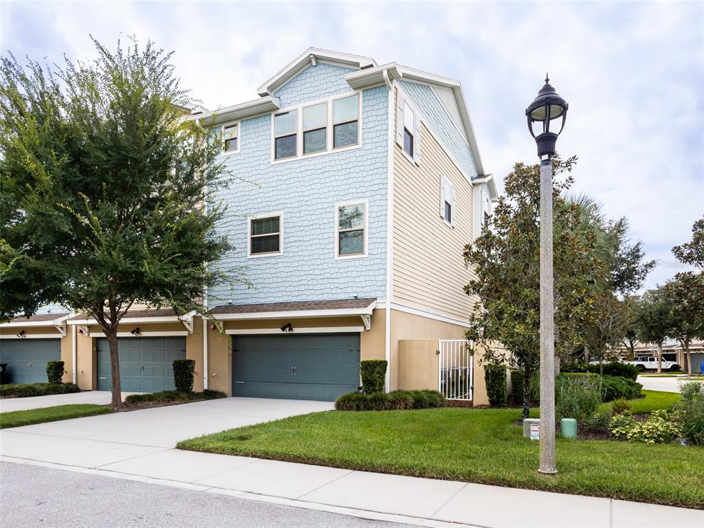 A three-story townhouse with blue shingle siding, a two-car garage, and a front lawn — 459 PORTICO COURT, OVIEDO, FL