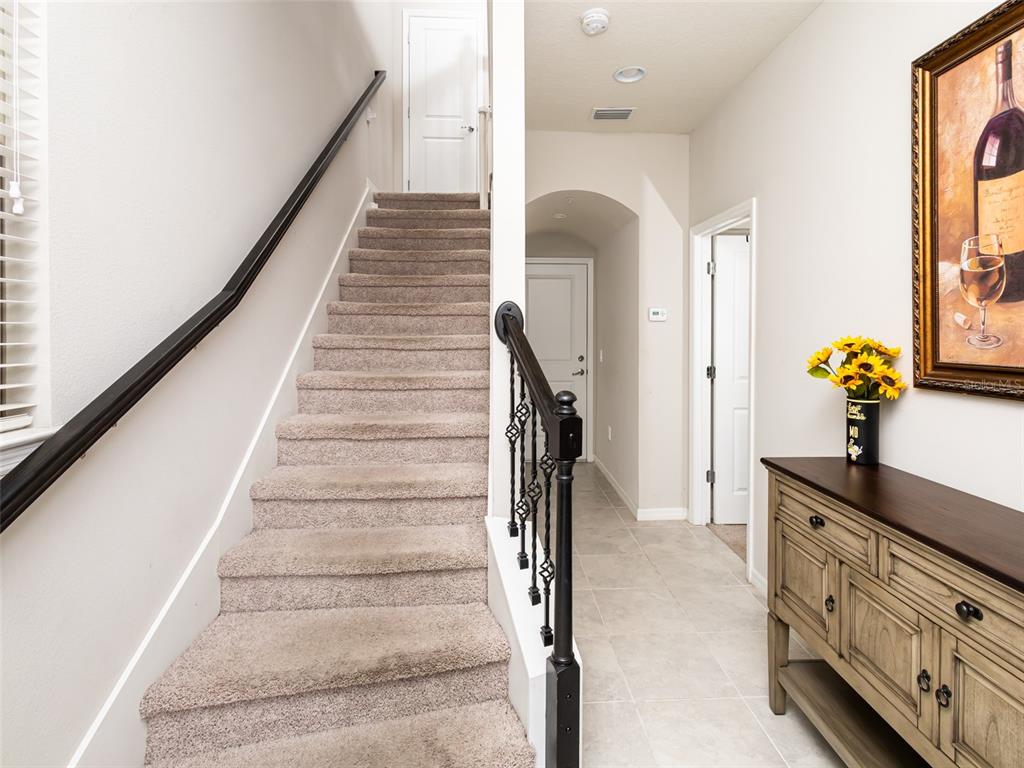 A carpeted staircase with a black railing leads to a landing next to a hallway — 459 PORTICO COURT, OVIEDO, FL