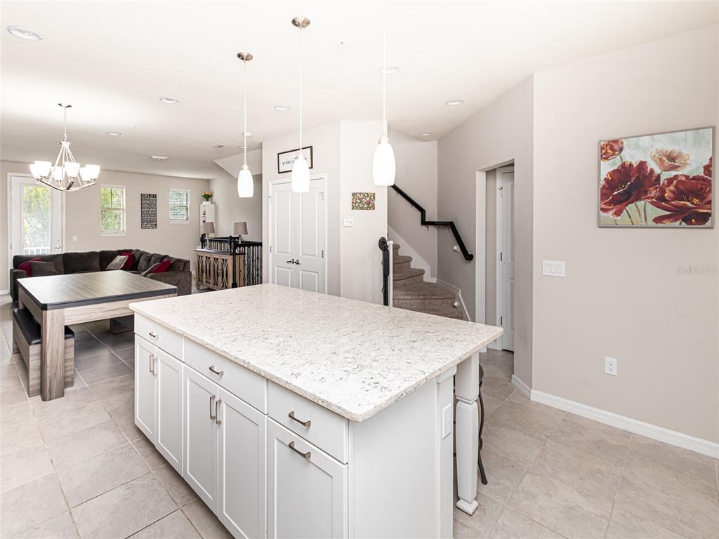 A kitchen island with a light-colored countertop sits in a room with tile flooring — 459 PORTICO COURT, OVIEDO, FL