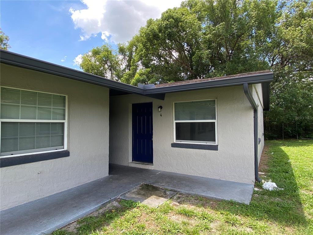 The exterior of a single-story house features a blue front door and a concrete walkway — 118 EATON STREET UNIT 4, EATONVILLE, FL