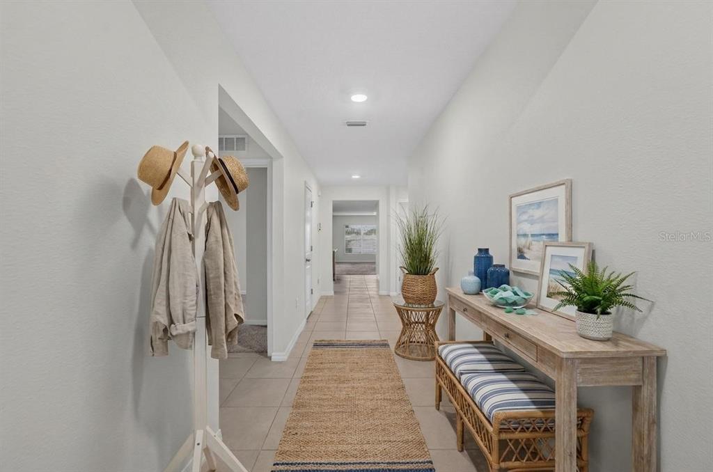 A hallway features tile flooring, a coat rack, and a console table with a bench — 1102 COASTAL HAMMOCK AVENUE, RUSKIN, FL
