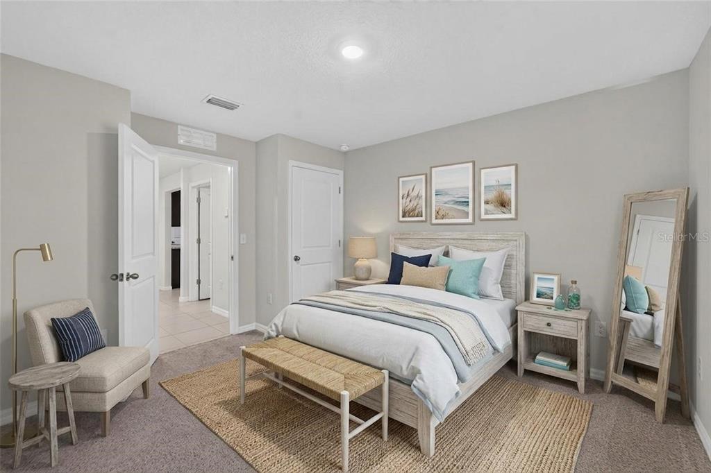 A bedroom features a bed with a wooden frame, a bench, and a floor mirror — 1102 COASTAL HAMMOCK AVENUE, RUSKIN, FL