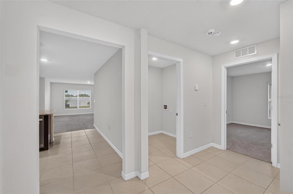 A hallway with tile flooring leads to a living area, a laundry closet, and a bedroom — 1102 COASTAL HAMMOCK AVENUE, RUSKIN, FL