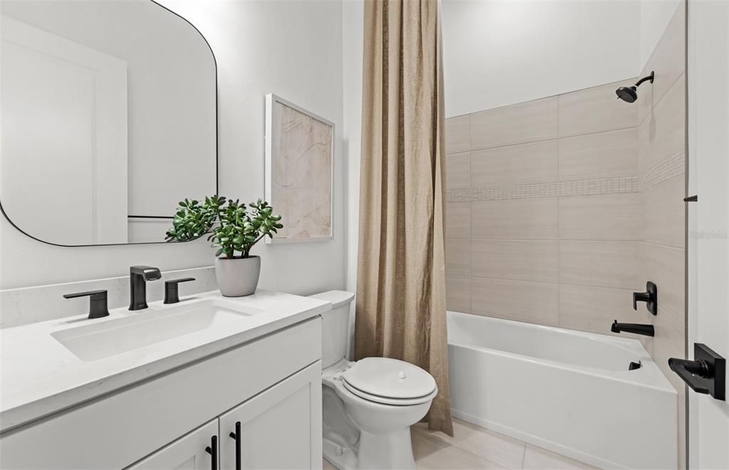 A bathroom features a white vanity, a toilet, and a bathtub with beige tiled walls — 4829 LONG POINT RUN, LAKEWOOD RANCH, FL