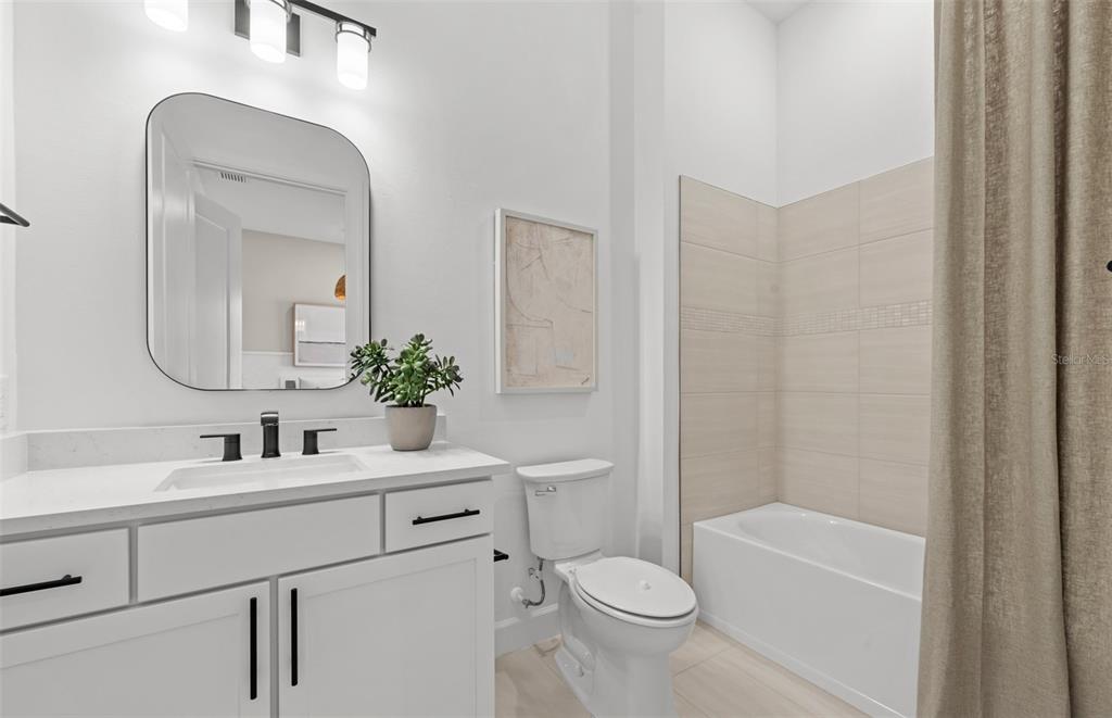 A bathroom features a white vanity, a rectangular mirror, a toilet, and a tiled tub — 4829 LONG POINT RUN, LAKEWOOD RANCH, FL