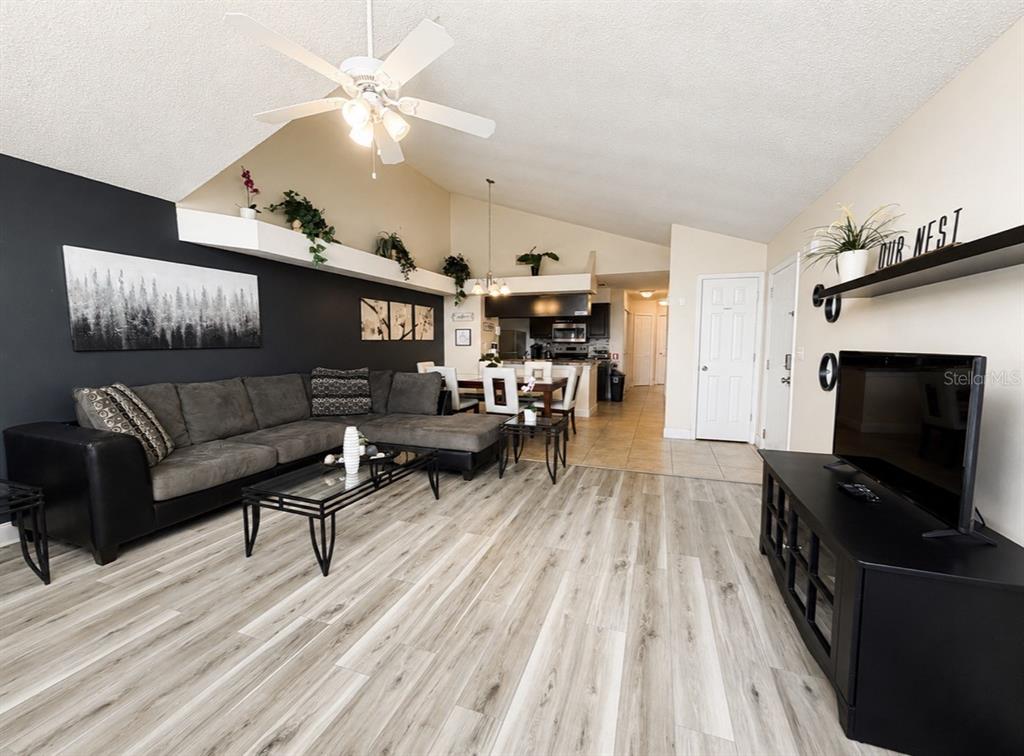 A living room features a dark accent wall, gray sectional sofa, and light wood flooring — 2747 N POINCIANA BOULEVARD UNIT 10, KISSIMMEE, FL