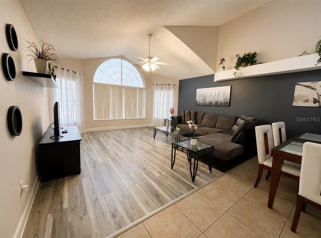A living room with wood-look flooring, a vaulted ceiling, and a large arched window — 2747 N POINCIANA BOULEVARD UNIT 10, KISSIMMEE, FL