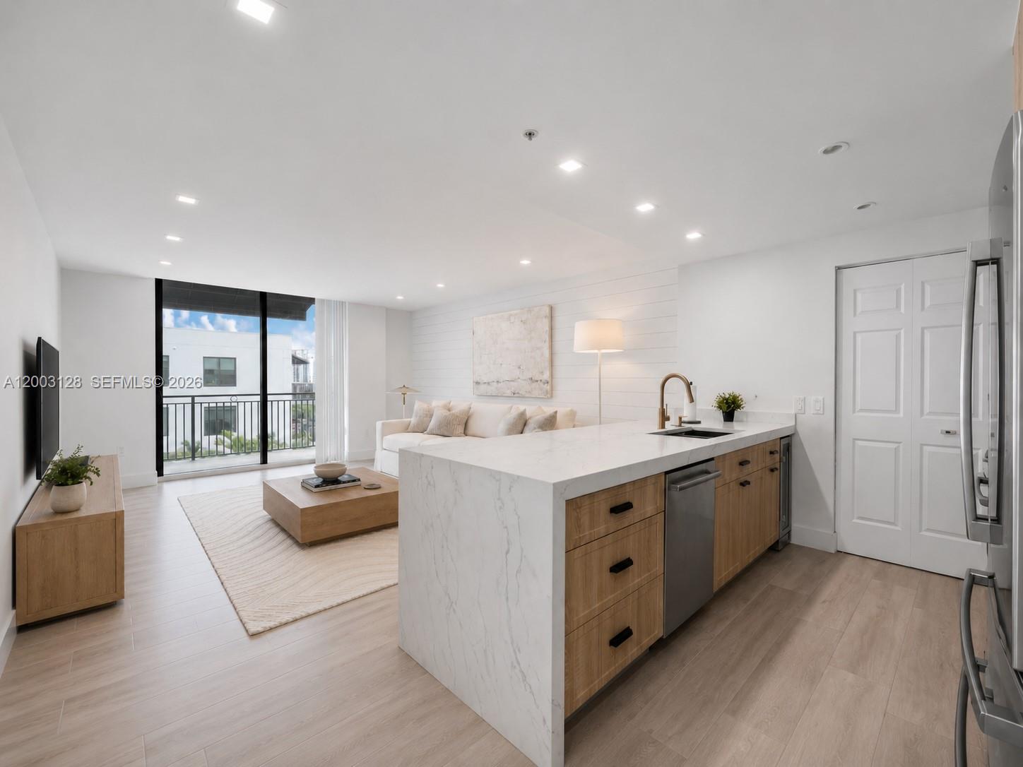 A modern open-concept living room and kitchen featuring light wood floors and marble countertops — 1300 Ponce De Leon Blvd # 815, Coral Gables FL 33134, CORAL GABLES, FL