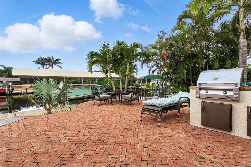 A screened-in swimming pool with a pink flamingo float overlooks a canal and boat dock — 9402 MIGUE CIRCLE, PORT CHARLOTTE, FL