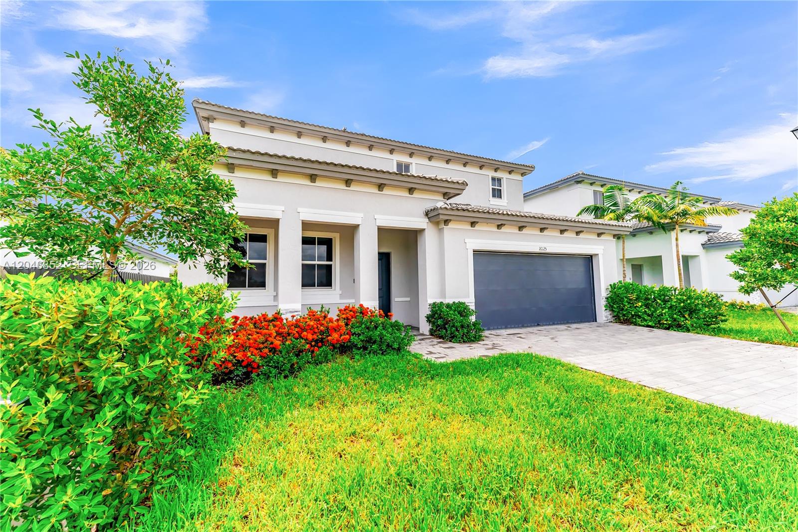 A two-story suburban house features a gray garage, light-colored stucco walls, and landscaped front yard — 16125 SW 149th Ave, Miami FL 33187, MIAMI, FL