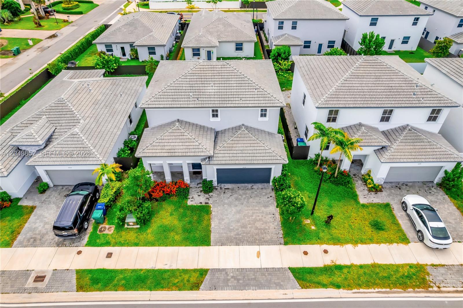 An aerial view shows three suburban houses with gray tiled roofs and paved driveways — 16125 SW 149th Ave, Miami FL 33187, MIAMI, FL