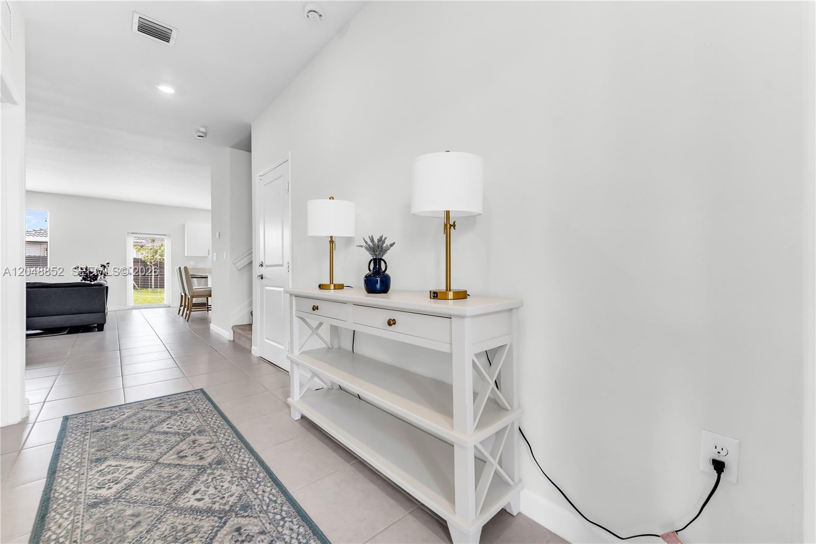A white console table with two lamps sits in a hallway with tile flooring — 16125 SW 149th Ave, Miami FL 33187, MIAMI, FL
