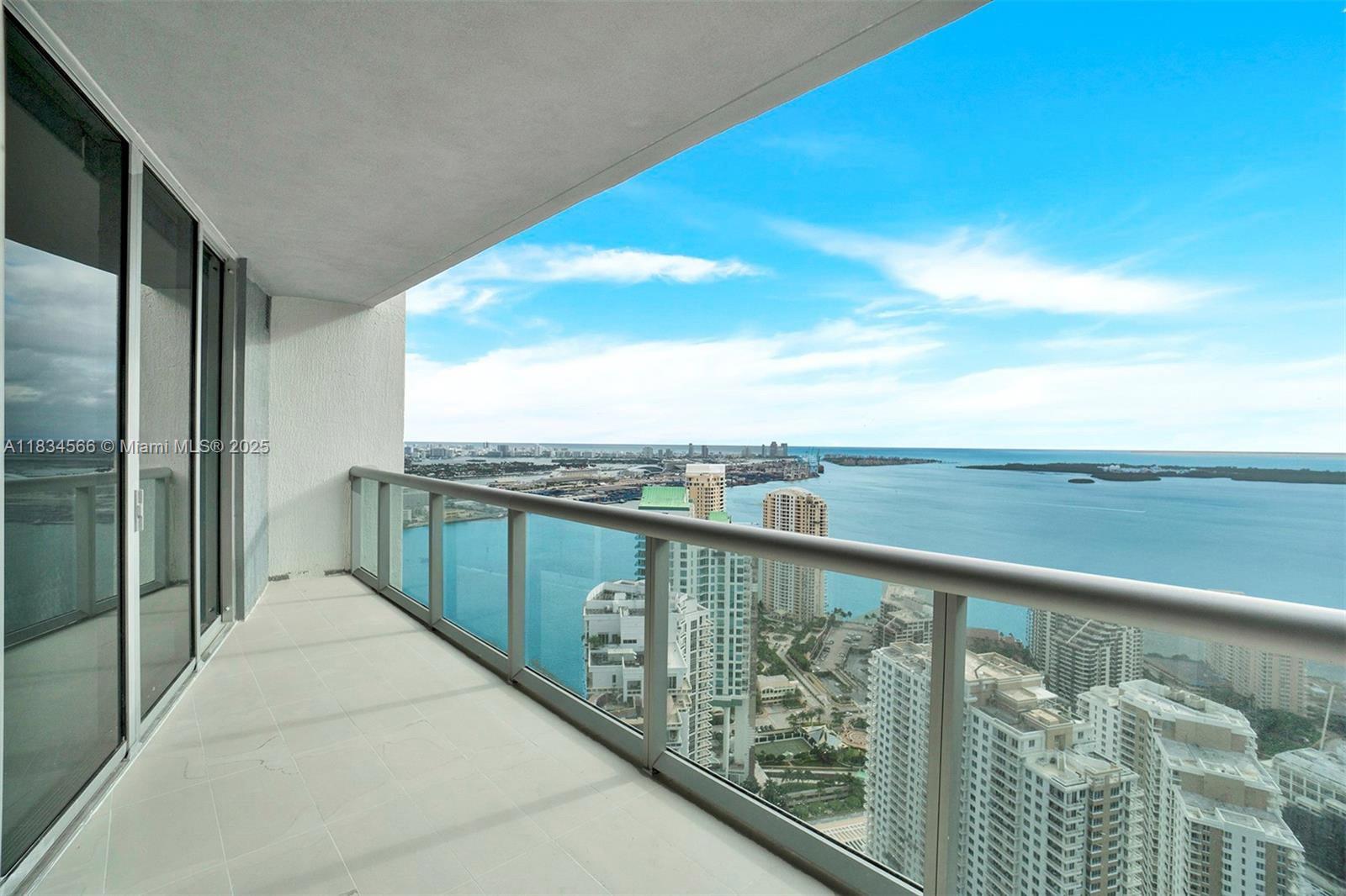 A high-rise balcony with a glass railing overlooks a city skyline and the ocean — 465 Brickell Ave # 4505, Miami FL 33131, MIAMI, FL