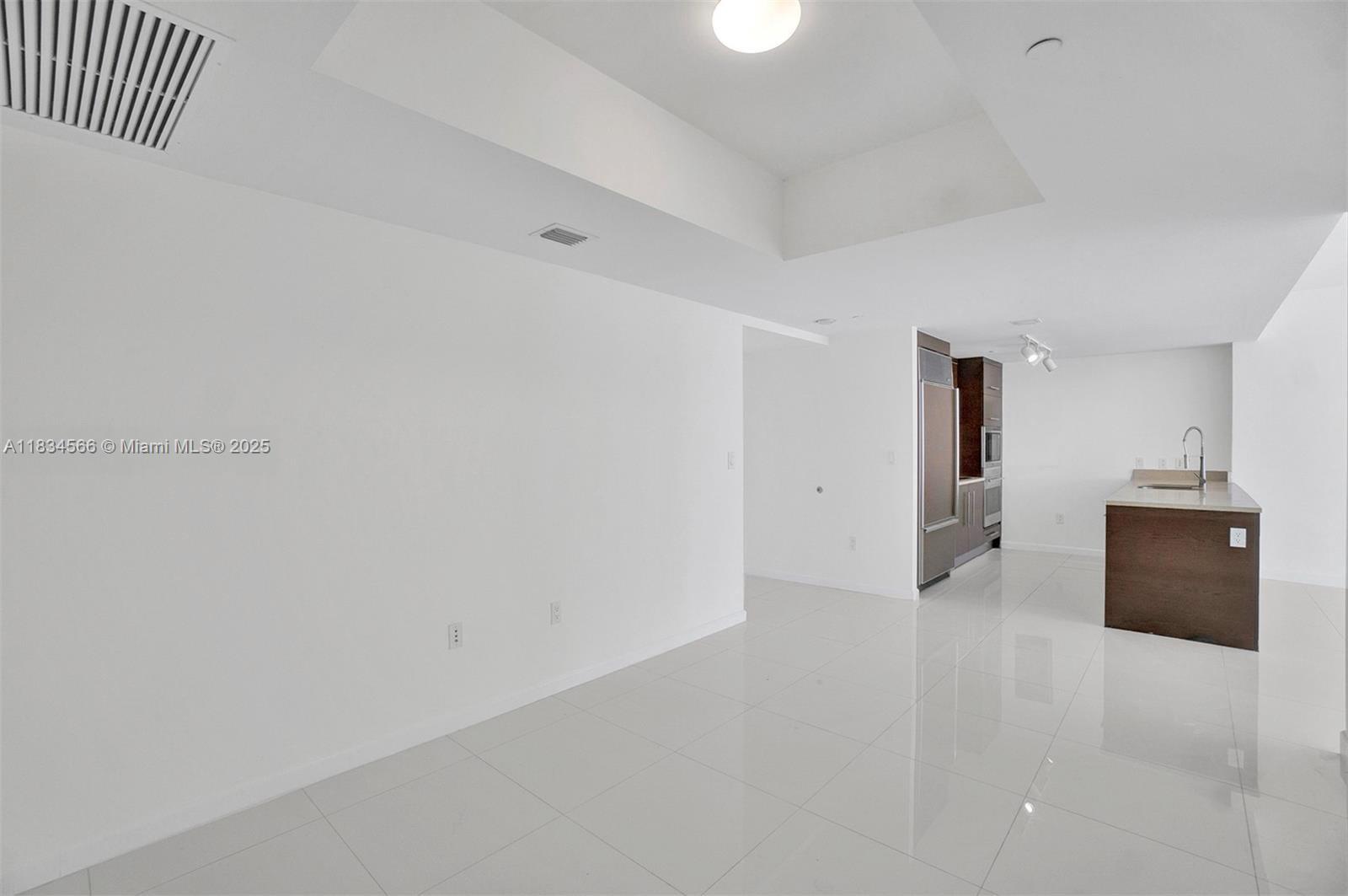 This open-concept living area features white tile flooring, a recessed ceiling, and a modern kitchen — 465 Brickell Ave # 4505, Miami FL 33131, MIAMI, FL