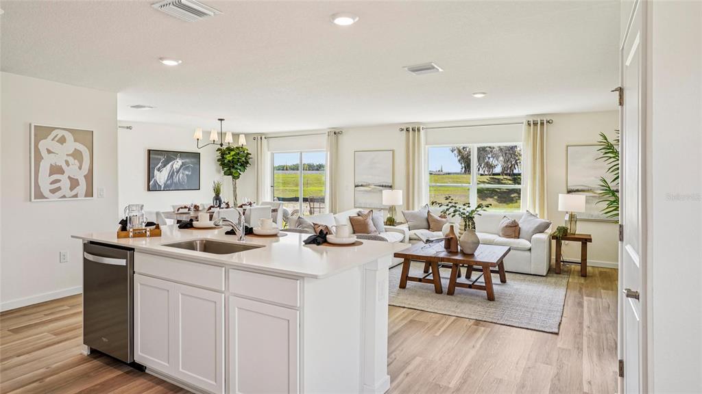 A kitchen island with a sink overlooks an open-concept living area with a view outside — 9080 SW 47TH COURT, OCALA, FL