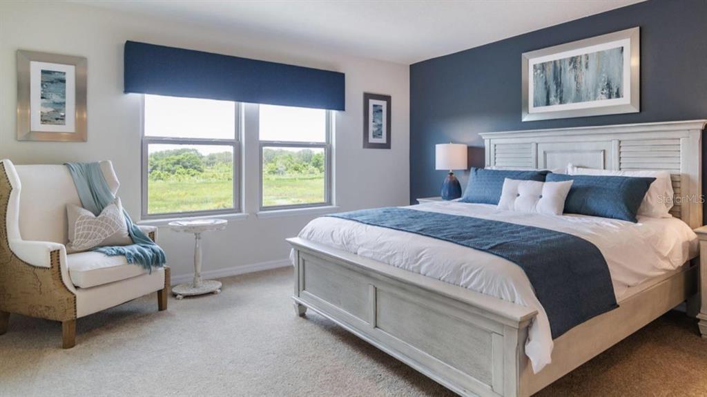 A bedroom features a king-sized bed, a blue accent wall, and a white armchair — 2452 DUBAI ST, KISSIMMEE, FL