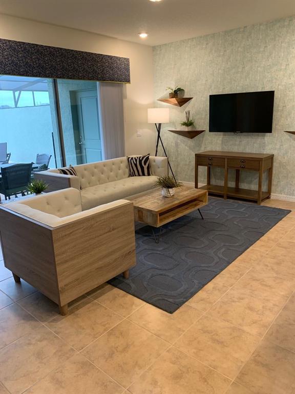 A living room features a tufted sofa, wooden armchair, coffee table, and wall-mounted television — 2452 DUBAI ST, KISSIMMEE, FL