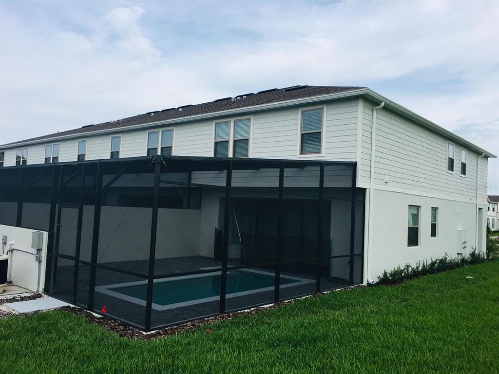 A two-story house with a screened-in pool enclosure and a grassy backyard — 2452 DUBAI ST, KISSIMMEE, FL
