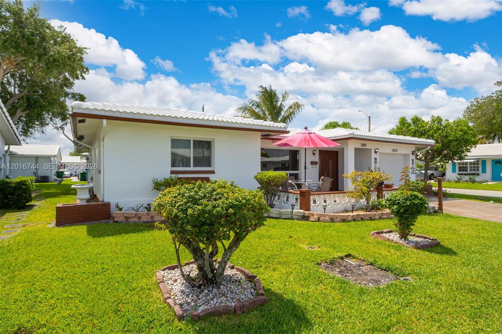 A white single-story house features a red umbrella on a small front patio — 5809 NW 83rd Ave, Tamarac FL 33321, TAMARAC, FL