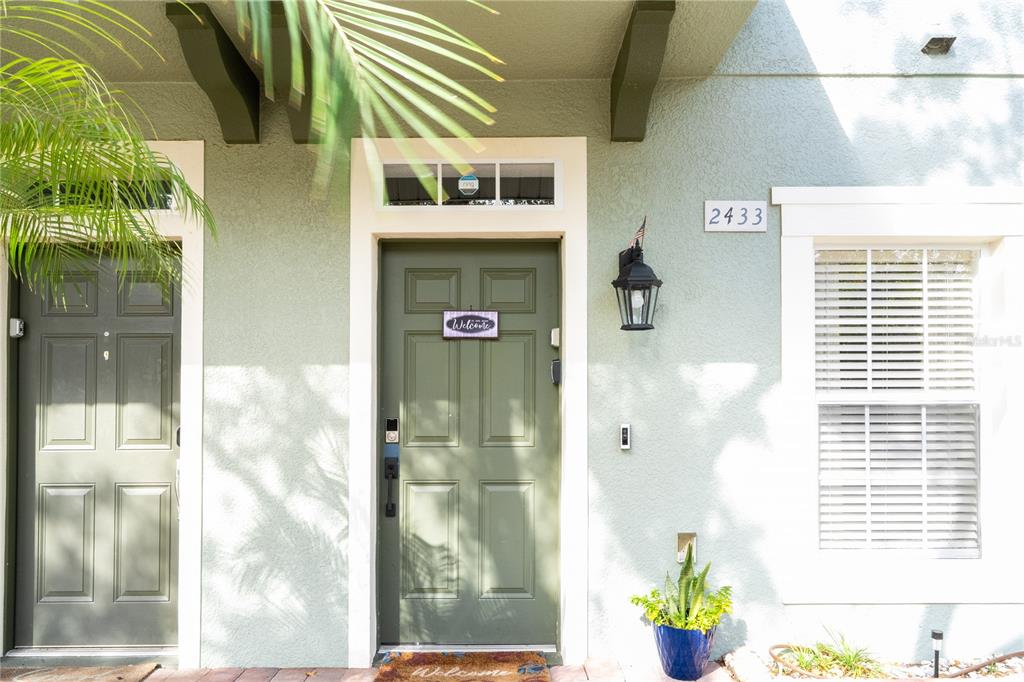 The exterior of a home features a green front door, a window, and a house number — 2433 CARAVELLE CIRCLE, KISSIMMEE, FL