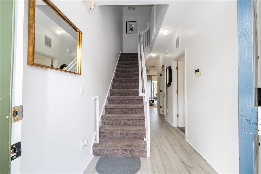 A carpeted staircase leads to an upper level in a bright, white-walled entryway — 2433 CARAVELLE CIRCLE, KISSIMMEE, FL