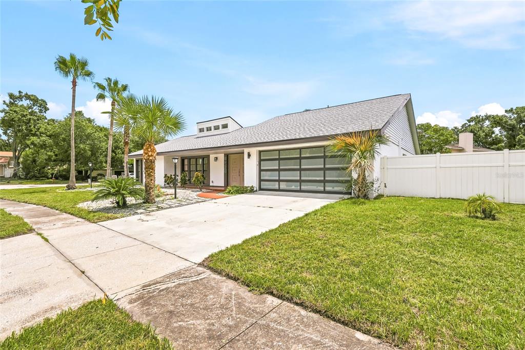 A single-story house with a white exterior, a modern garage door, and a front lawn — 8215 LA SERENA DRIVE, TAMPA, FL