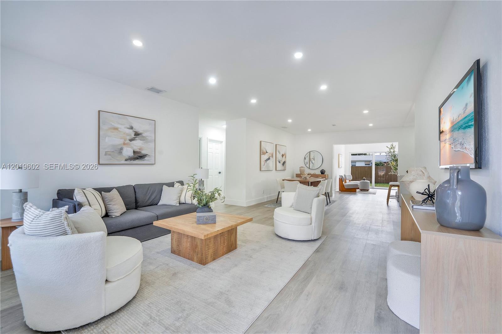 A bright, open-concept living and dining area features white walls, light wood flooring, and modern furniture — 40 SE 3RD TERR, Dania Beach FL 33004, DANIA BEACH, FL