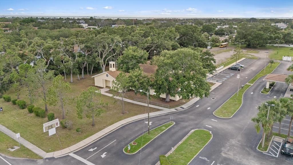 An aerial view shows a light-colored building with a small steeple surrounded by trees — 4704 KELLY ROAD, TAMPA, FL