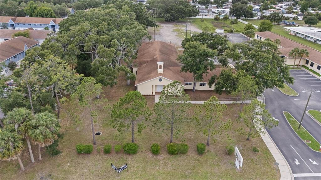 An aerial view shows a tan building with a brown roof surrounded by trees — 4704 KELLY ROAD, TAMPA, FL
