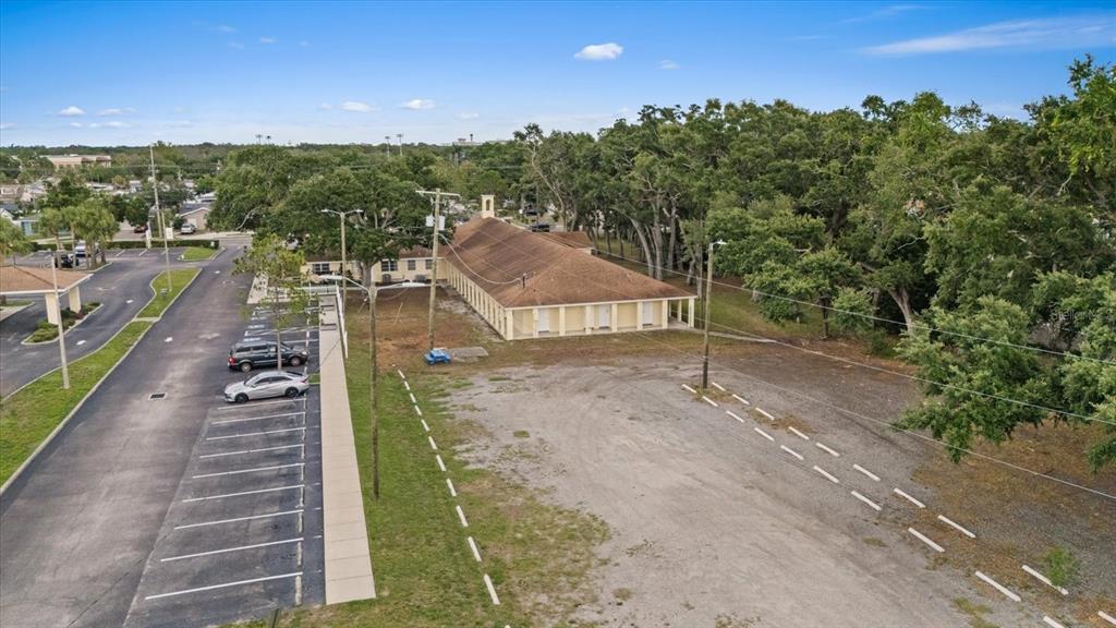 An aerial view shows a long, single-story building with a parking lot and wooded area — 4704 KELLY ROAD, TAMPA, FL