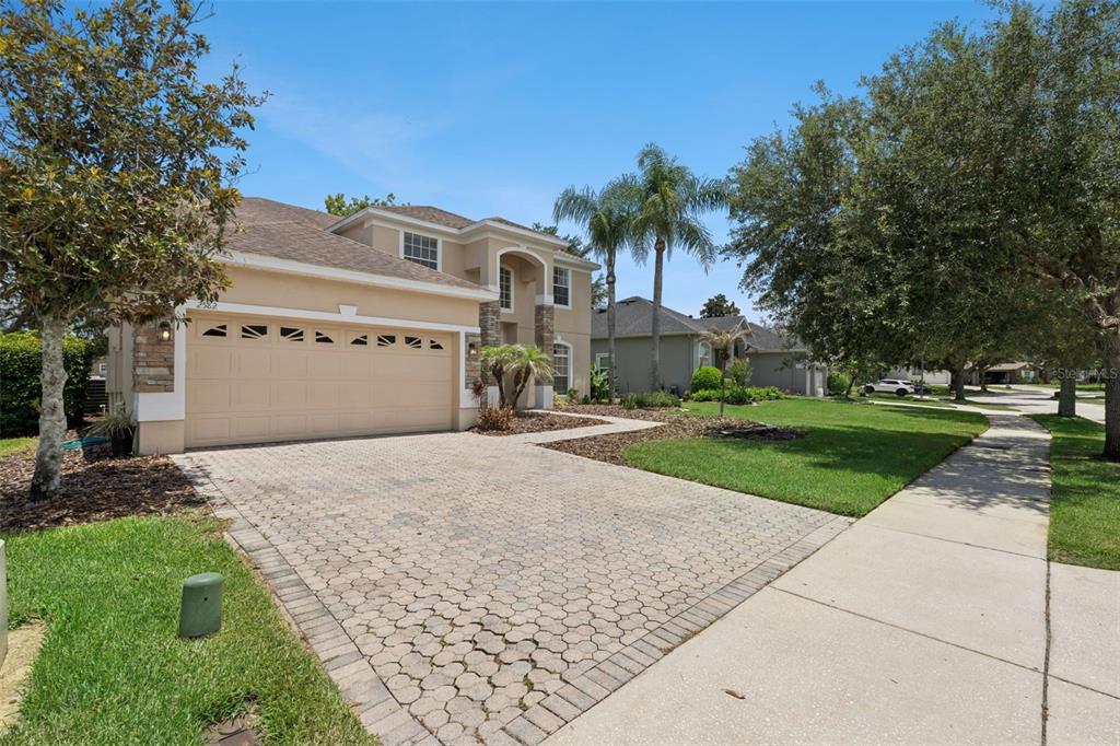 A two-story house with a beige stucco exterior, stone accents, and a paved driveway — 2582 DOUBLE TREE PLACE, OVIEDO, FL