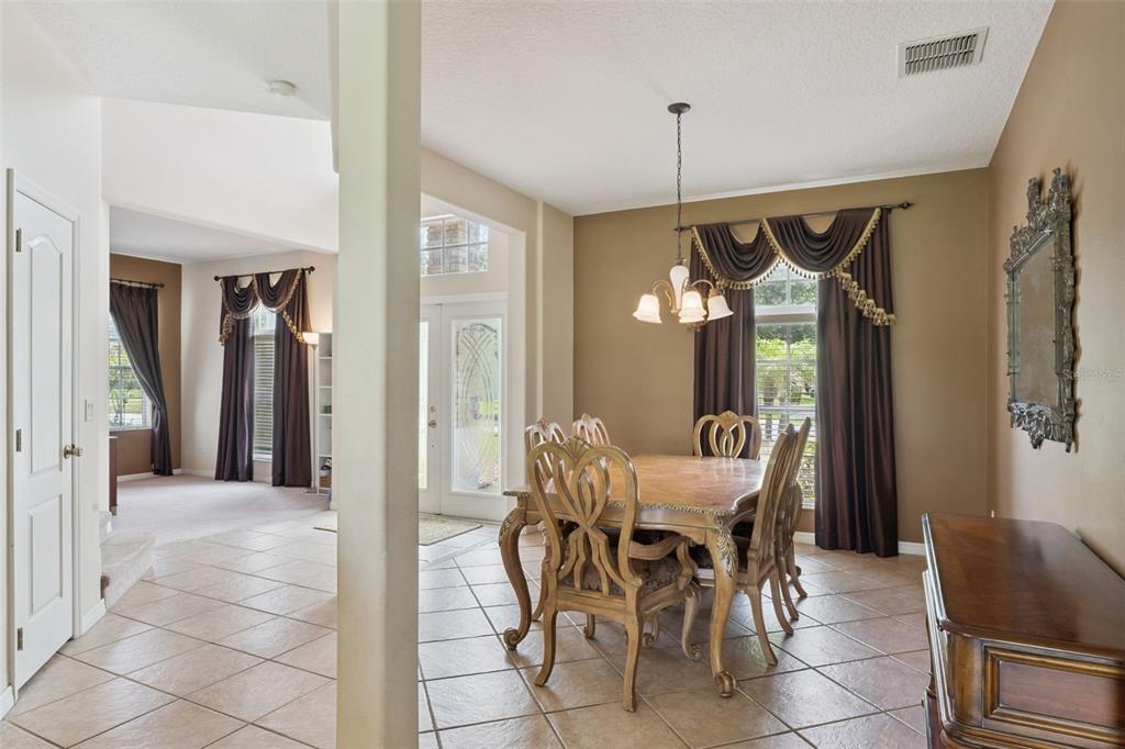 A dining room with tile floors, a wooden table set, and dark brown window curtains — 2582 DOUBLE TREE PLACE, OVIEDO, FL
