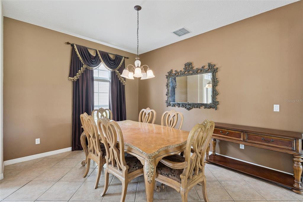 A dining room features a wooden table with six chairs, a chandelier, and a wall mirror — 2582 DOUBLE TREE PLACE, OVIEDO, FL