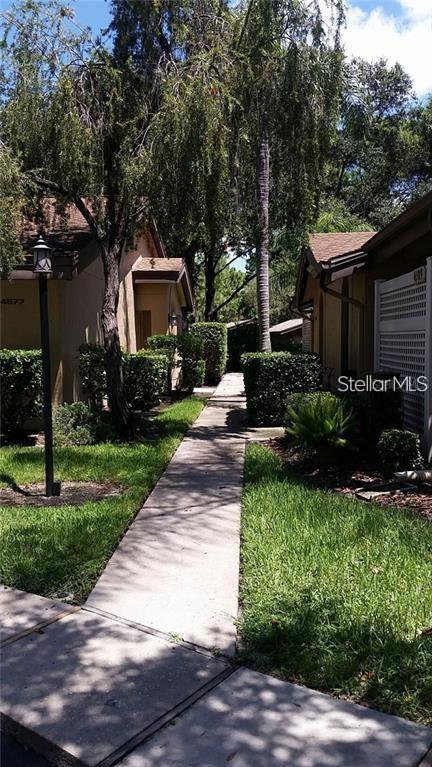 A concrete walkway leads between two residential buildings surrounded by trees and manicured hedges — 4581 MORNINGSIDE UNIT 21, SARASOTA, FL