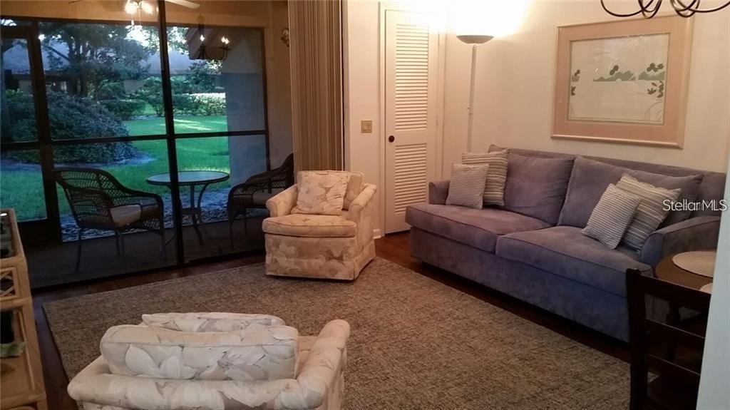 A living room features a blue sofa, two patterned armchairs, and a sliding glass door — 4581 MORNINGSIDE UNIT 21, SARASOTA, FL