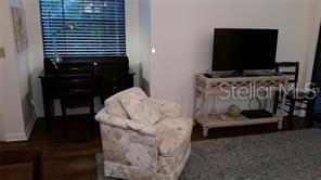 A living room features a patterned armchair, a dark wood desk, and a television on a console — 4581 MORNINGSIDE UNIT 21, SARASOTA, FL