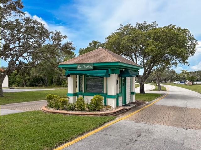 A small guardhouse with a green roof and trim sits at the entrance of a community — 7686 ST ANDREWS BOULEVARD, WEEKI WACHEE, FL